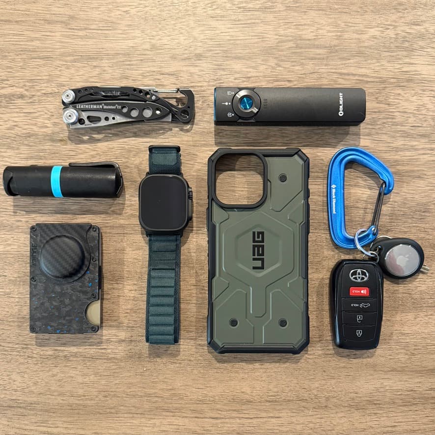 Everyday carry tools including a flashlight, multitool, wallet, watch, and phone